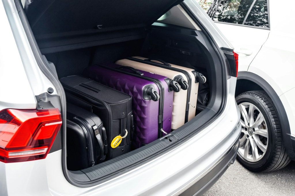 An image of an open car boot with multiple suitcases packed neatly inside.